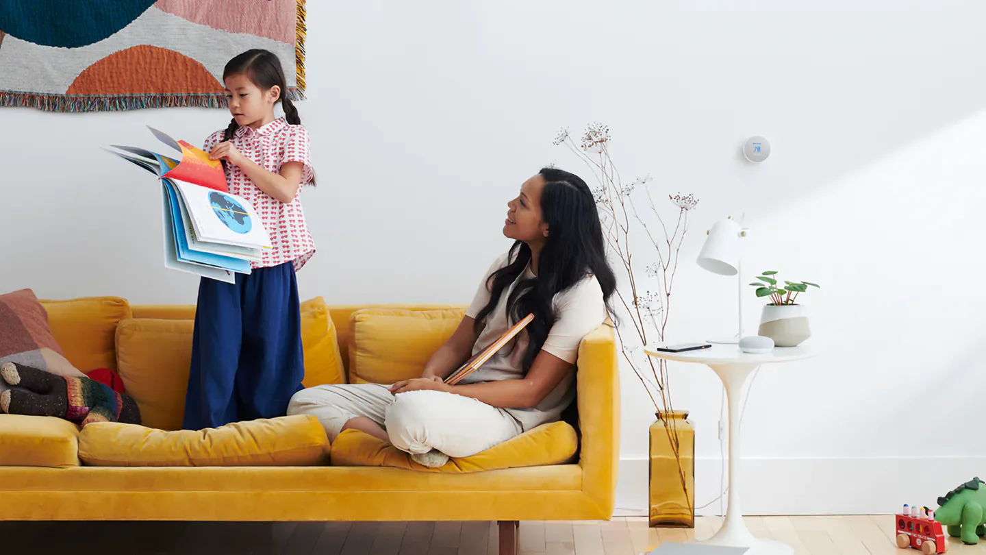 A parent and child beside a Google smart speaker using Gemini for Home