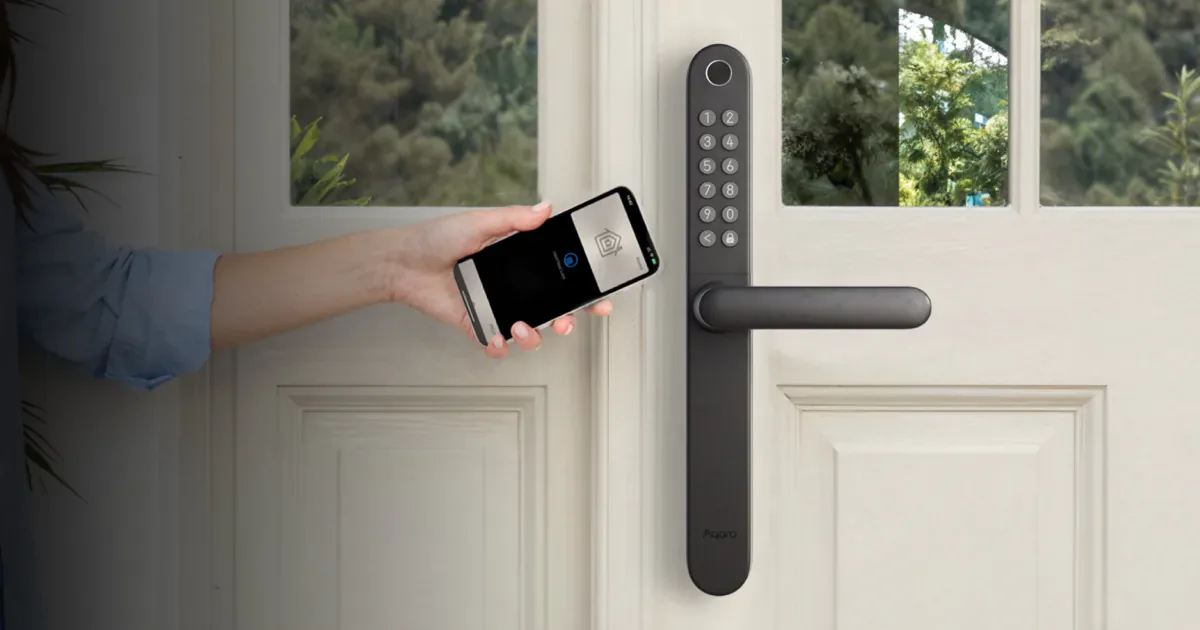 A hand holding an iPhone up to the Aqara Smart Lock U600 keypad handle on a white front door